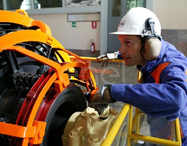Operaio, con casco, occhiali protettivi e cuffie antirumore, in sala macchine controlla il funzionamento dell'eccitatrice di una turbina