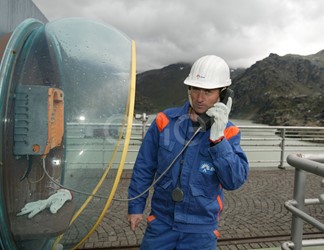 Operaio al telefono sul coronamento della diga di Alpe Gera