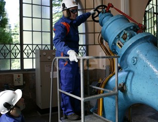 Operai, con casco, occhiali protettivi e cuffie antirumore, in sala macchine controllano il gruppo turboalternatore
