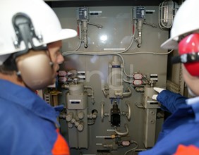 Due Operai, con casco, occhiali protettivi e cuffie antirumore, al lavoro in sala macchine