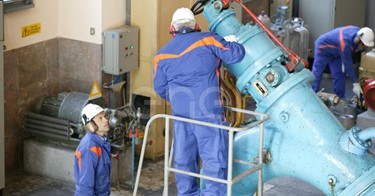 Operai, con casco, occhiali protettivi e cuffie antirumore, in sala macchine controllano il gruppo turboalternatore