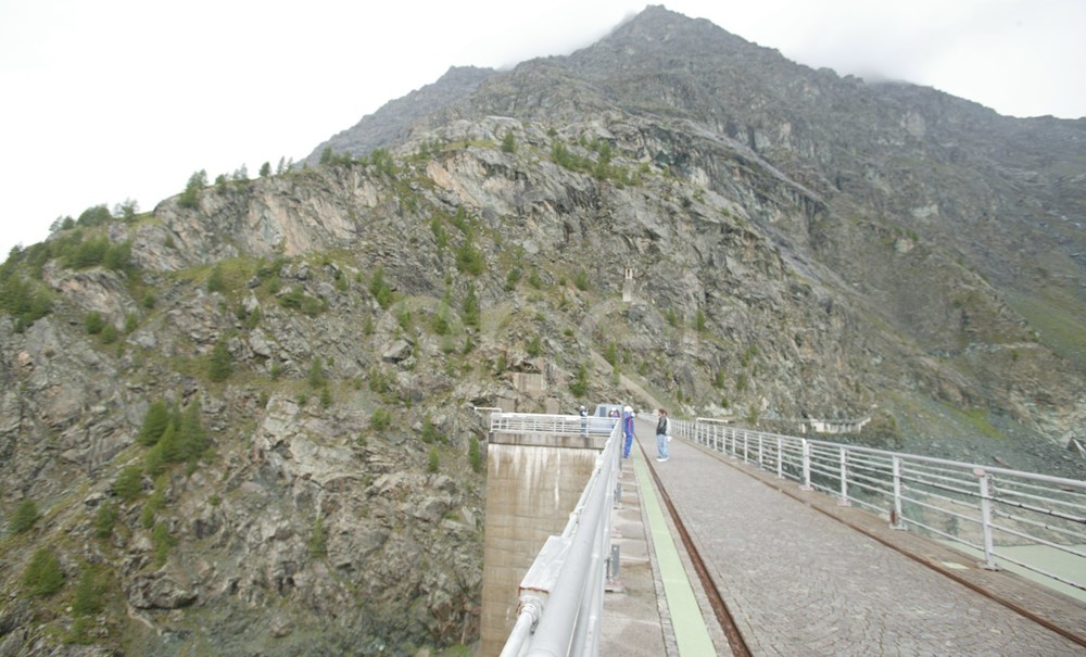 Coronamento della diga di Alpe Gera con operaio e turisti