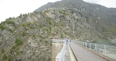Coronamento della diga di Alpe Gera con operaio e turisti