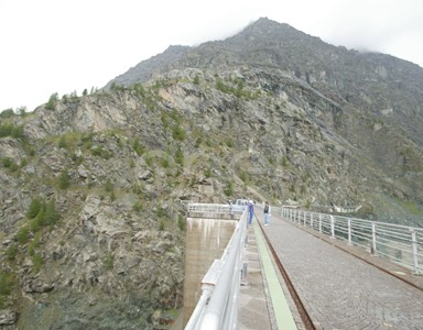 Coronamento della diga di Alpe Gera con operaio e turisti