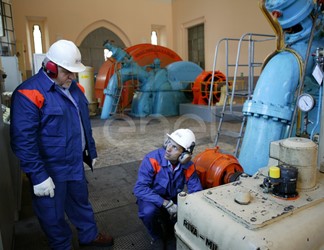 Due Operai, con casco, occhiali protettivi e cuffie antirumore, al lavoro in sala macchine