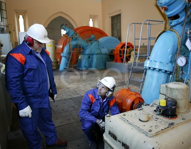 Due Operai, con casco, occhiali protettivi e cuffie antirumore, al lavoro in sala macchine