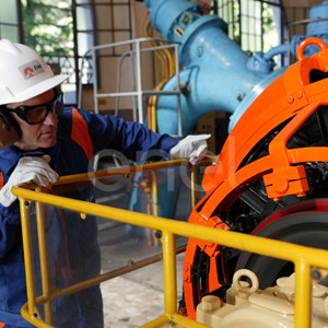 Operaio, con casco, occhiali protettivi e cuffie antirumore, in sala macchine controlla il funzionamento dell'eccitatrice di una turbina