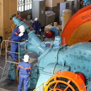 Operai, con casco, occhiali protettivi e cuffie antirumore, in sala macchine controllano il gruppo turboalternatore