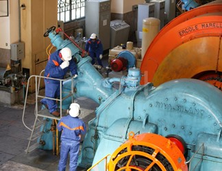 Operai, con casco, occhiali protettivi e cuffie antirumore, in sala macchine controllano il gruppo turboalternatore