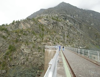 Coronamento della diga di Alpe Gera con operaio e turisti