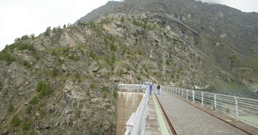 Coronamento della diga di Alpe Gera con operaio e turisti