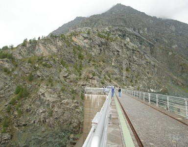 Coronamento della diga di Alpe Gera con operaio e turisti