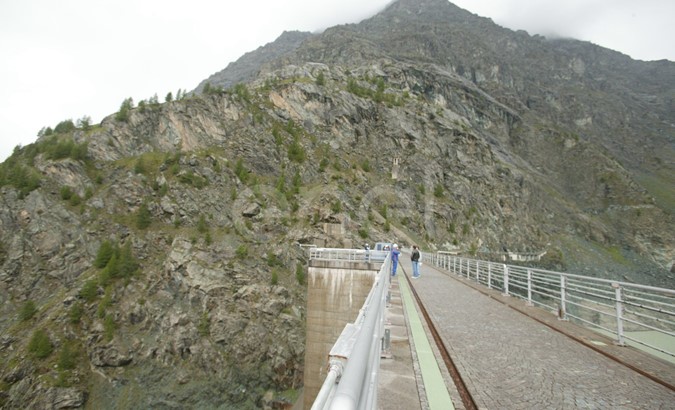 Coronamento della diga di Alpe Gera con operaio e turisti