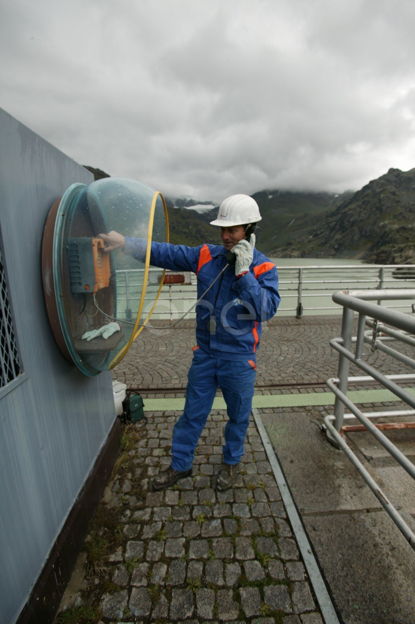 Operaio al telefono sul coronamento della diga di Alpe Gera